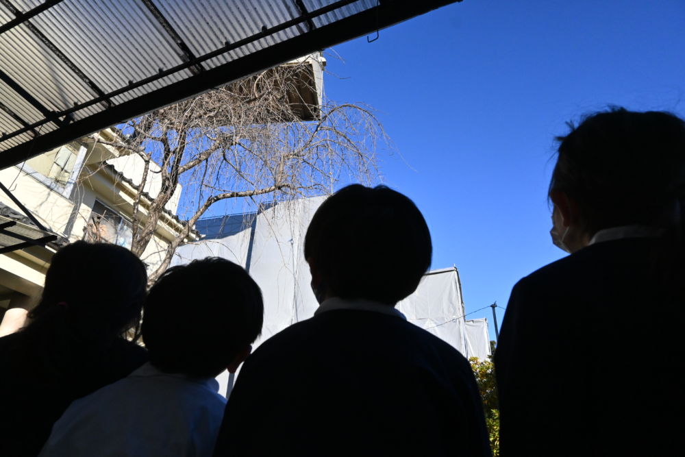 クレーン車で吊るされたプレハブを見て大興奮な子どもたち